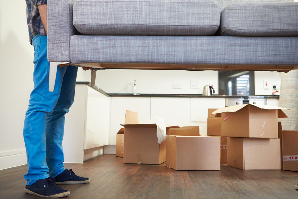 man picking up and end of a couch