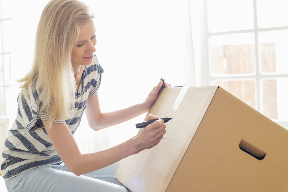 get organized! lady writing on a cardboard moving box