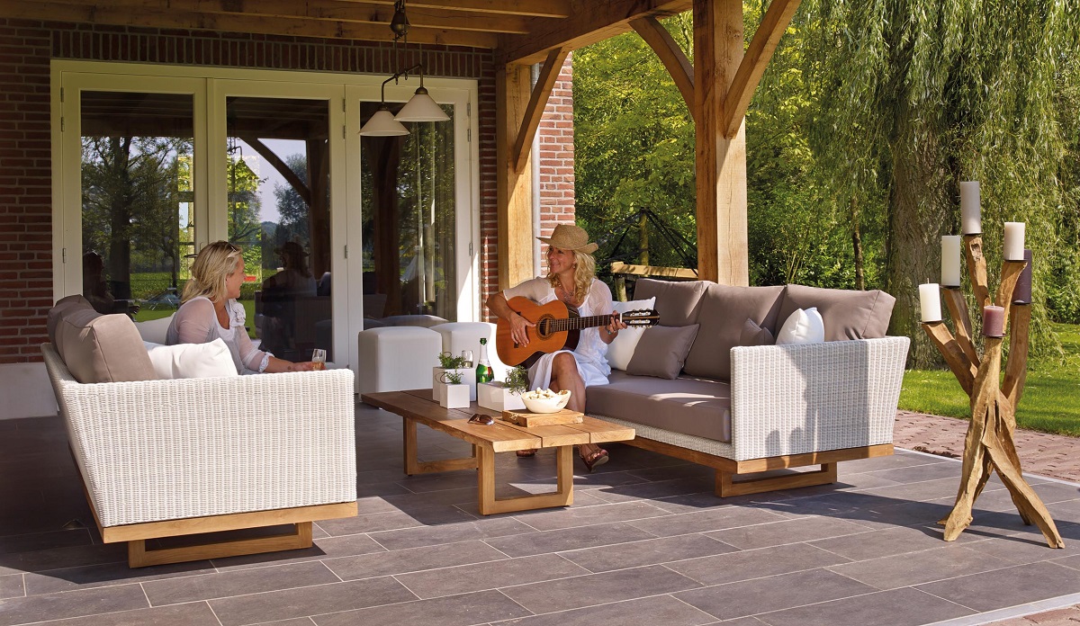 women sitting in outdoor furniture playing a guitar
