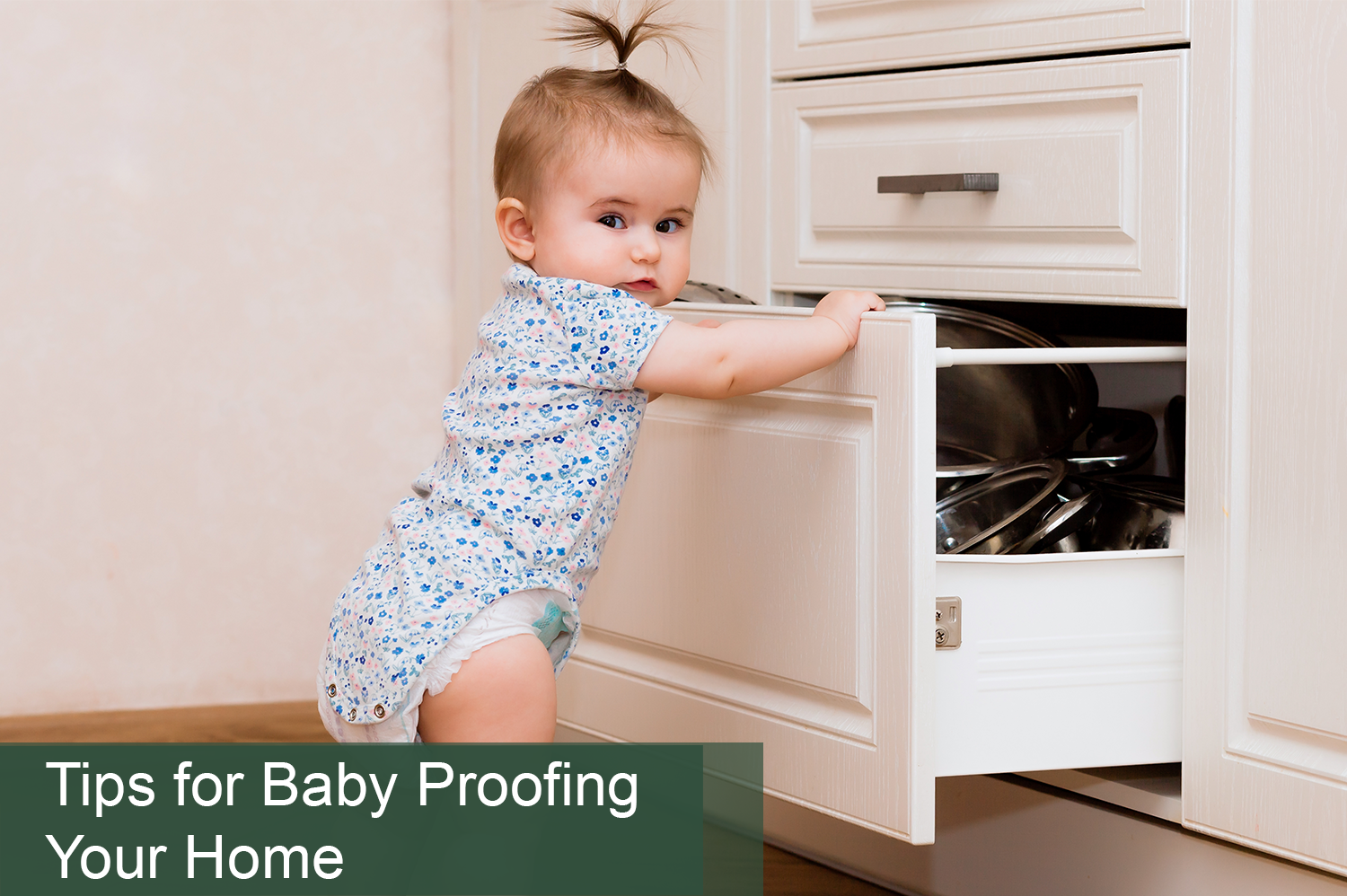 Baby girl in onesie opening kitchen cabinet; in need of baby proofing your home.