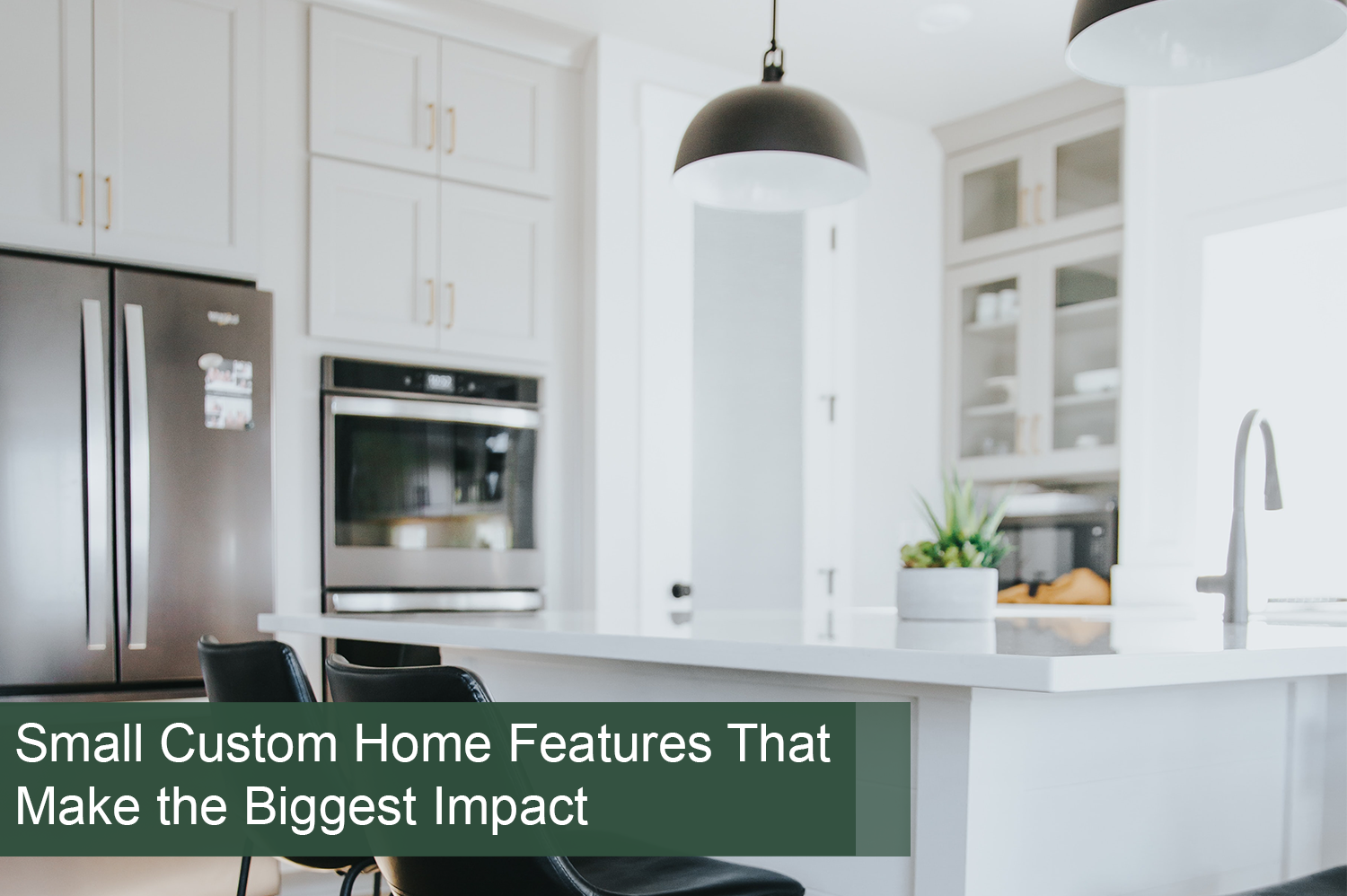 Kitchen in custom home with black hanging lights, white cabinets and white counter tops.