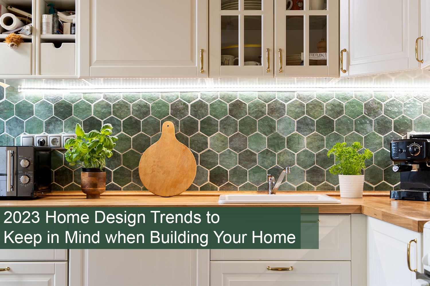 A kitchen with a green back splash, white cabinets, and gold hardware - a new home design trend to consider when building your home.